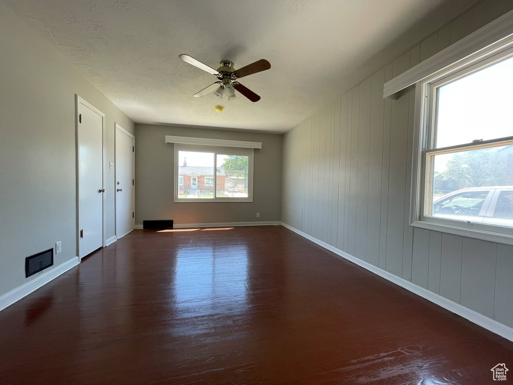 Empty room with wood finished floors, baseboards, and ceiling fan