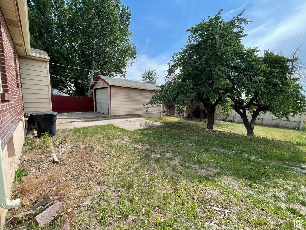View of yard with a garage, concrete driveway, and an outbuilding