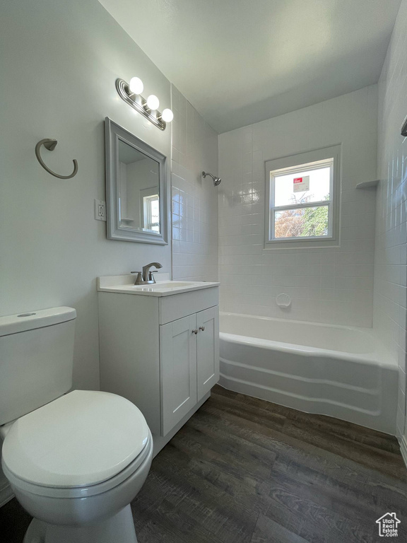 Full bath featuring vanity, toilet, wood finished floors, and tub / shower combination
