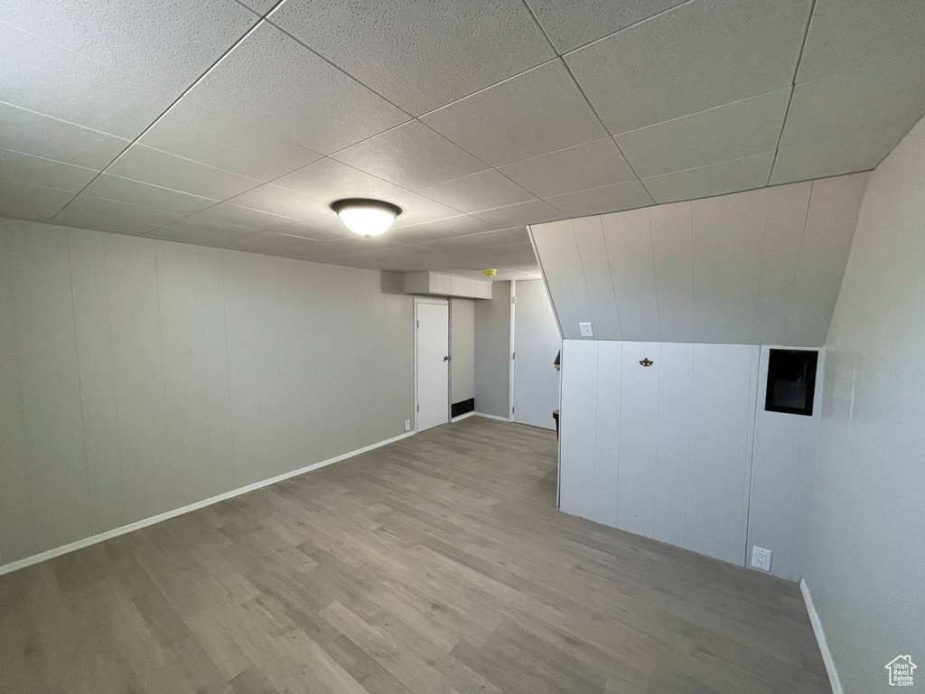 Finished basement featuring wood finished floors, baseboards, and a paneled ceiling