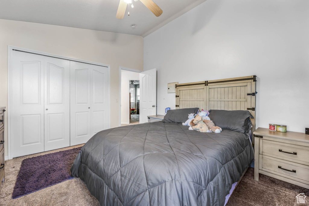 Carpeted bedroom featuring a closet, ceiling fan, and high vaulted ceiling