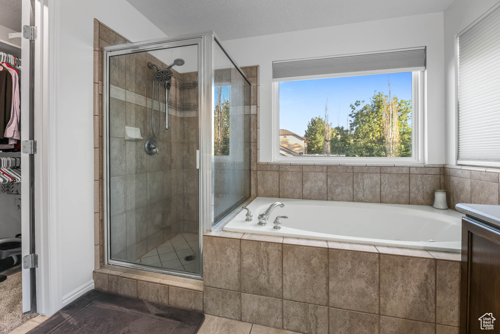 Full bathroom featuring a shower stall, a garden tub, a walk in closet, and vanity