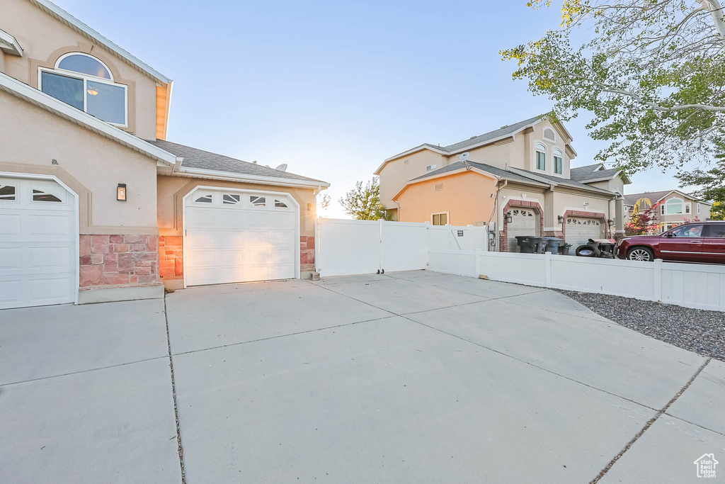 View of property exterior with driveway, stucco siding, a garage, and stone siding