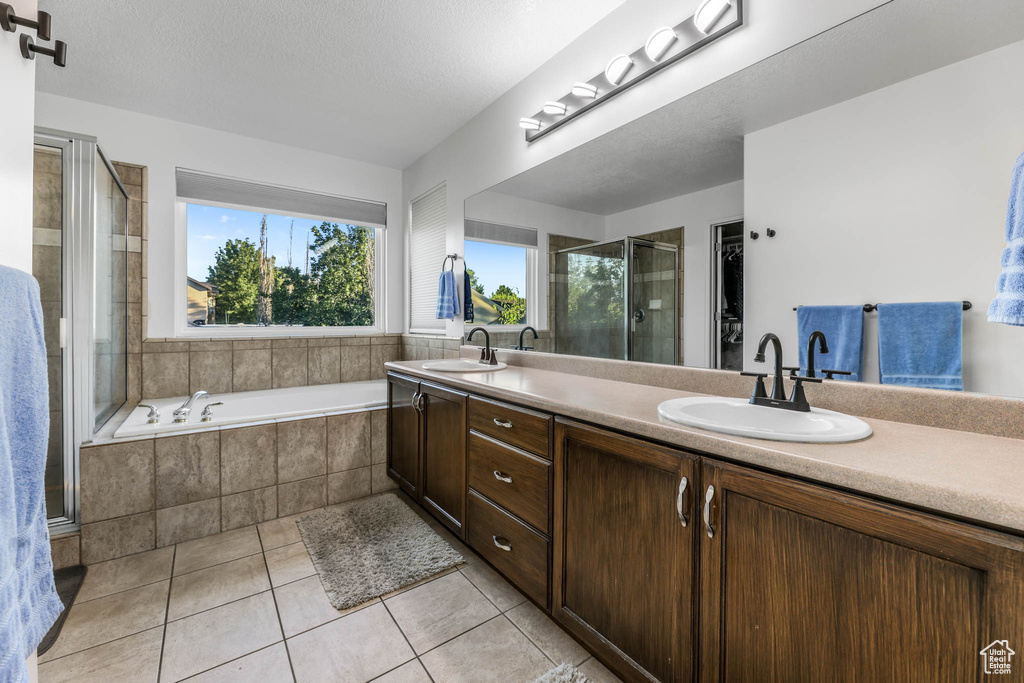 Bathroom with tile patterned flooring, a shower stall, double vanity, and a bath