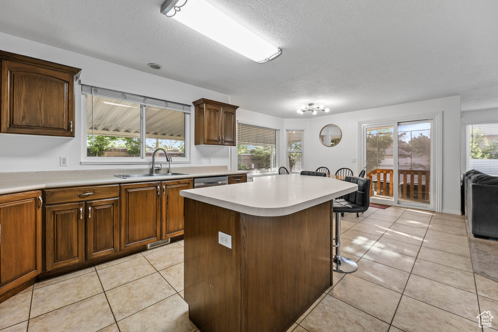 Kitchen with light countertops, a textured ceiling, a breakfast bar area, healthy amount of natural light, and light tile patterned floors