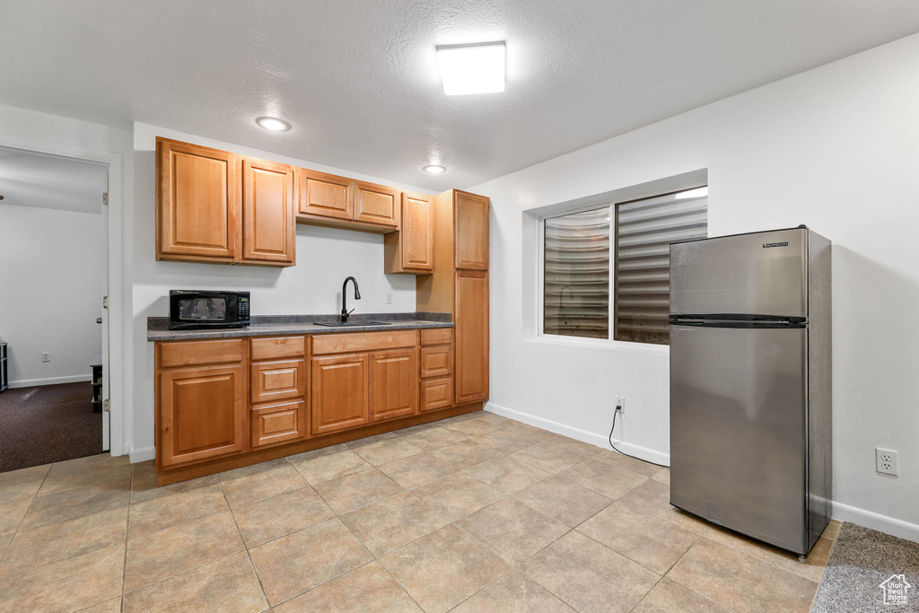 Kitchen with freestanding refrigerator, black microwave, dark countertops, and recessed lighting