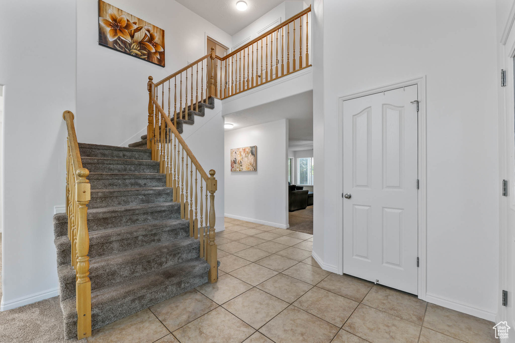 Stairs featuring tile patterned floors and a towering ceiling