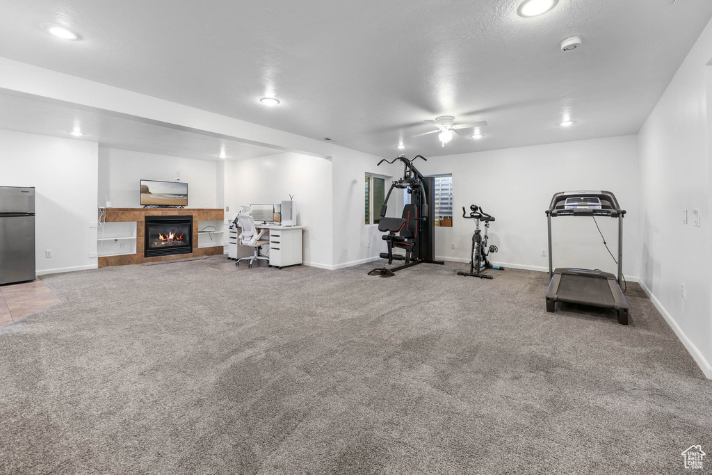 Workout room featuring carpet floors, a tile fireplace, ceiling fan, and recessed lighting