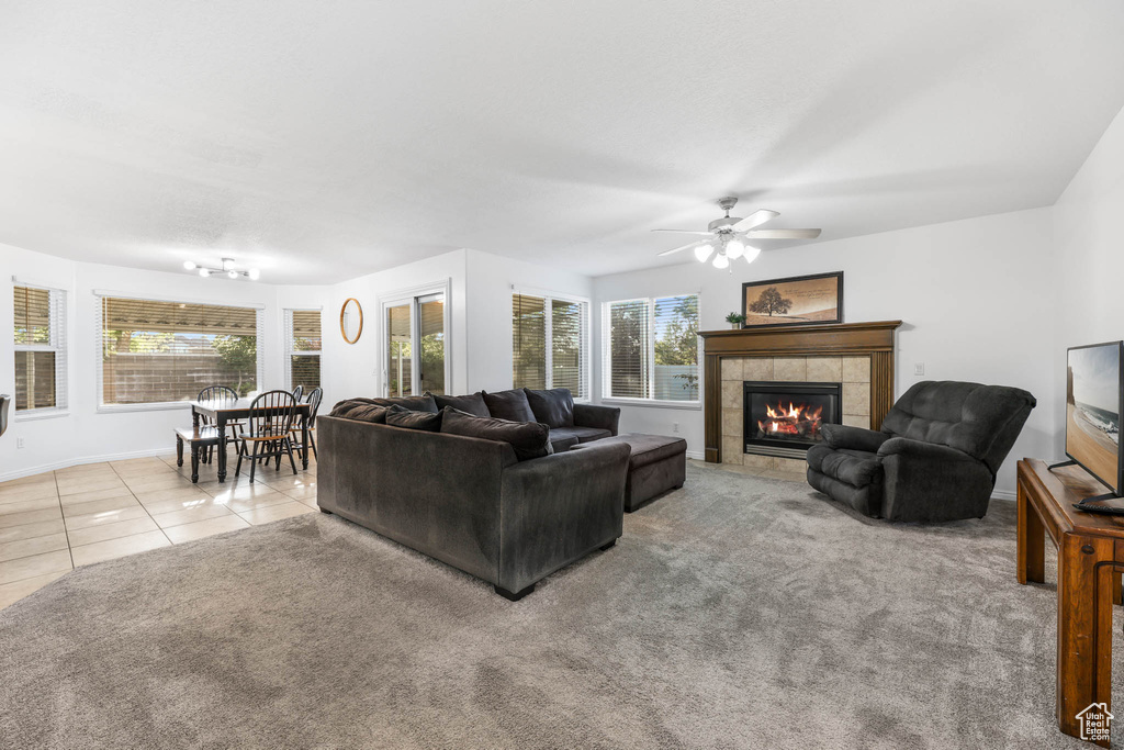 Carpeted living area with a fireplace, healthy amount of natural light, ceiling fan, and tile patterned flooring
