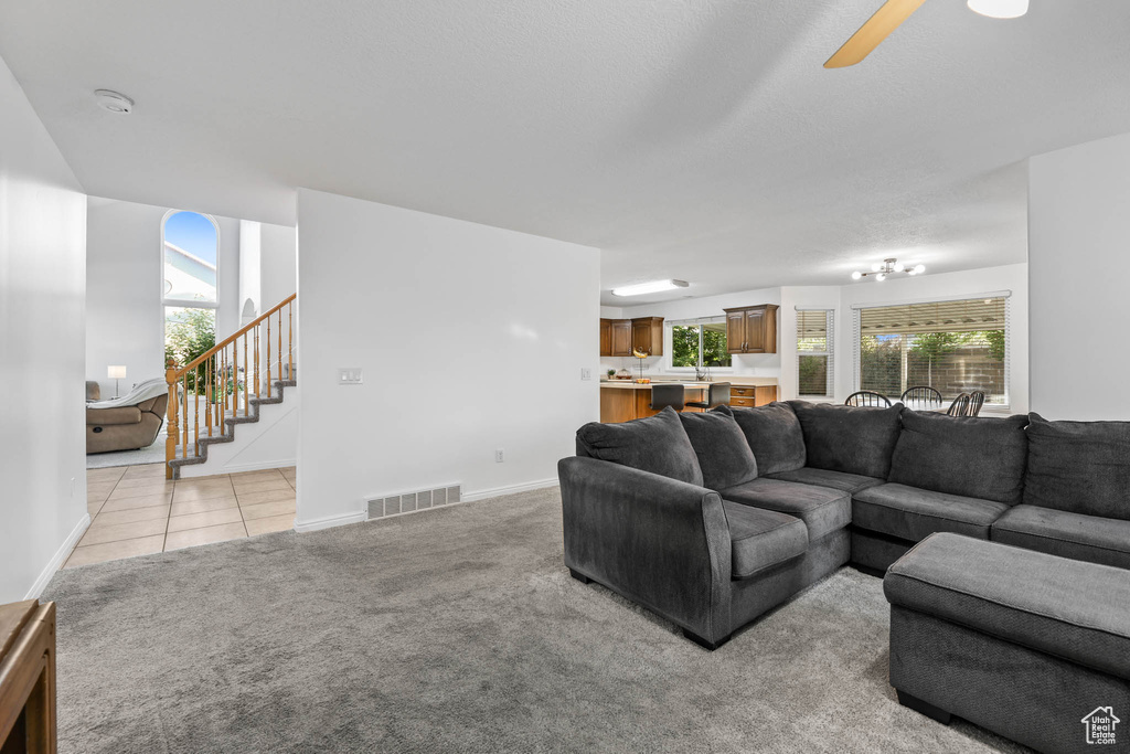 Living room featuring stairway, plenty of natural light, light colored carpet, and a ceiling fan
