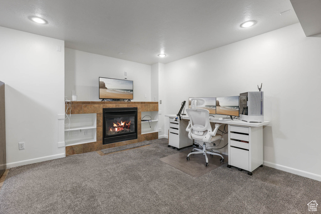 Carpeted office with a tiled fireplace and recessed lighting