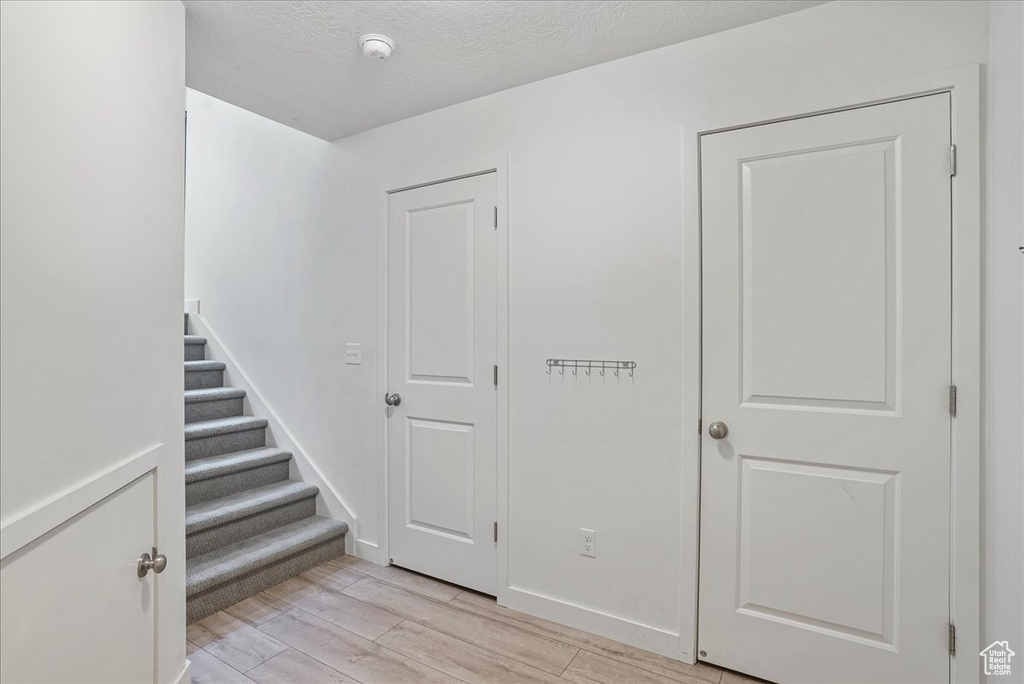Stairway with wood finished floors and a textured ceiling