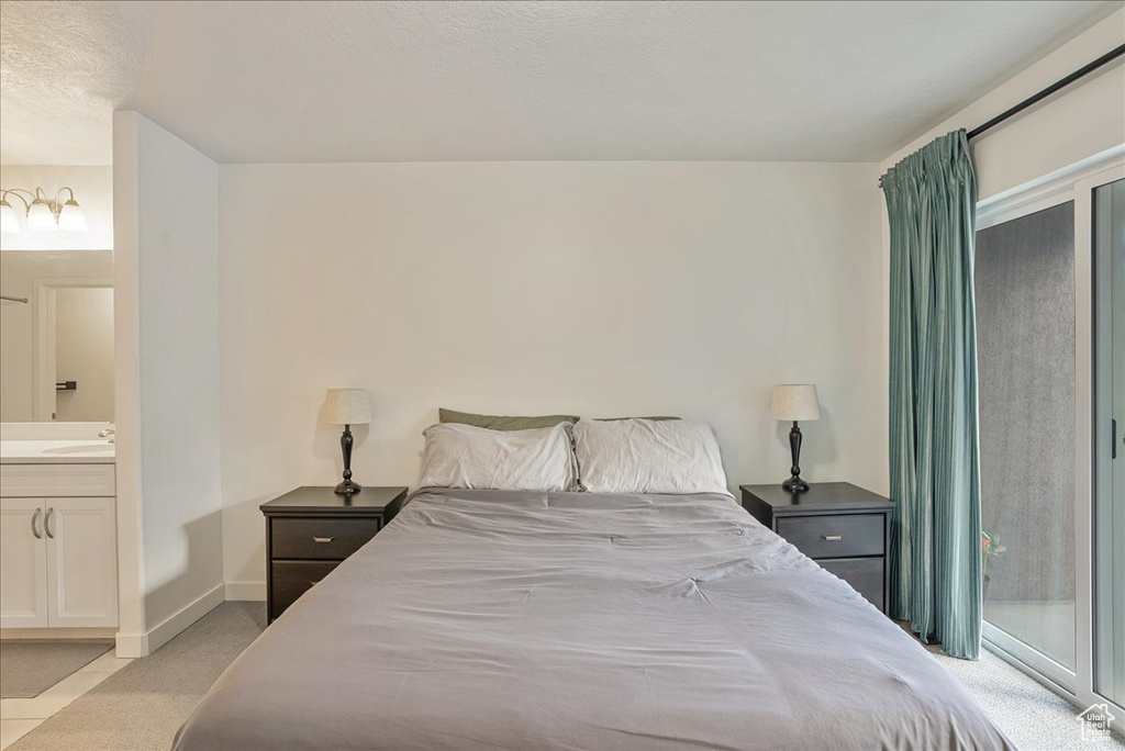 Bedroom with light colored carpet, ensuite bath, and access to exterior
