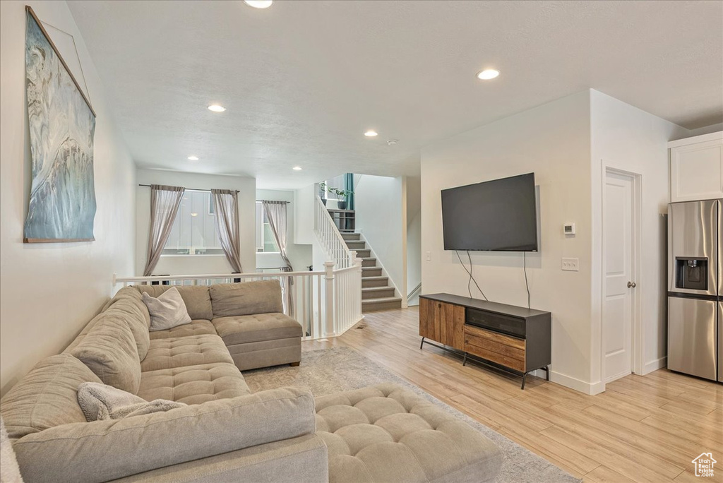 Living area with light wood finished floors, recessed lighting, and stairs