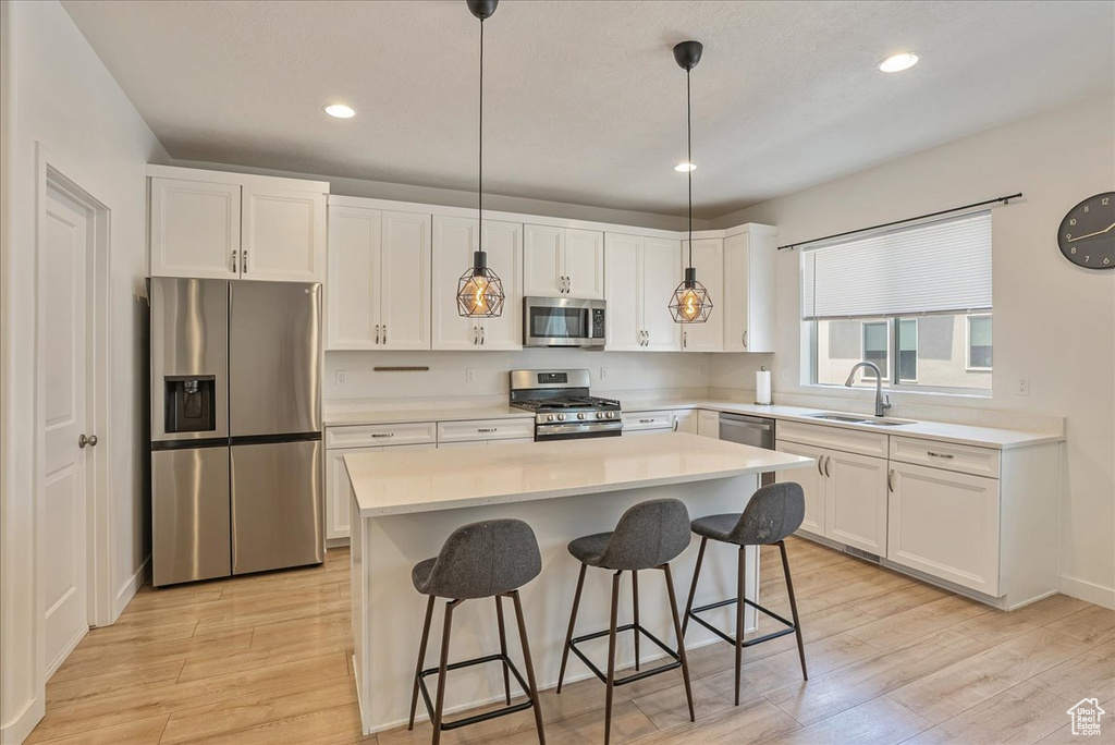 Kitchen with appliances with stainless steel finishes, light wood-style floors, white cabinets, and recessed lighting