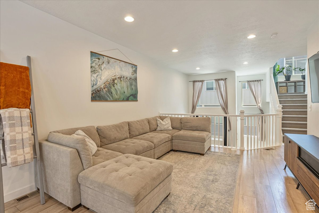 Living area with light wood-type flooring and recessed lighting