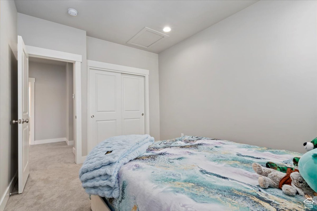 Bedroom featuring light colored carpet, a closet, and attic access