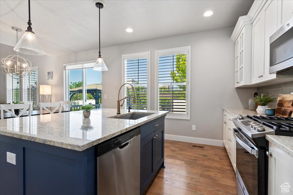 Kitchen featuring stainless steel appliances, light wood-style floors, blue cabinets, white cabinets, and recessed lighting