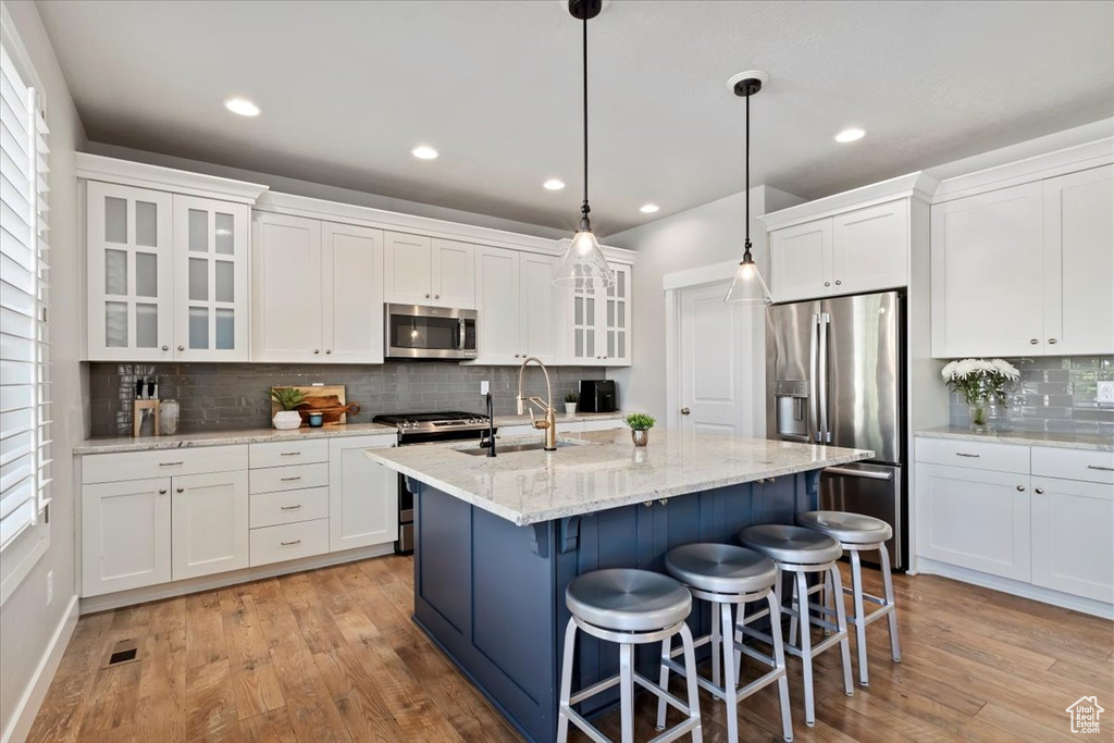 Kitchen featuring stainless steel appliances, light wood-type flooring, tasteful backsplash, white cabinetry, and recessed lighting