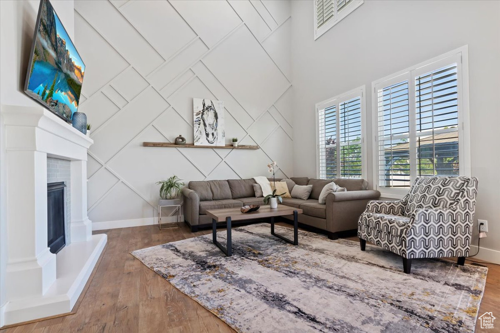 Living area with wood finished floors, a fireplace with raised hearth, and a decorative wall