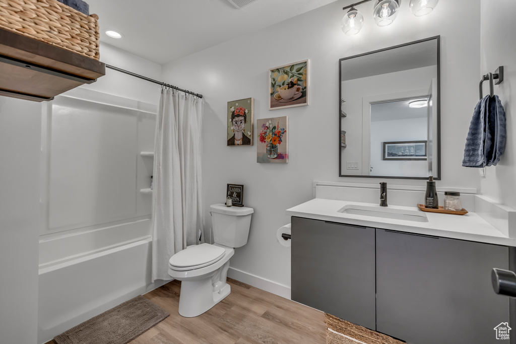 Full bath with vanity, wood finished floors, shower / bath combination with curtain, and recessed lighting