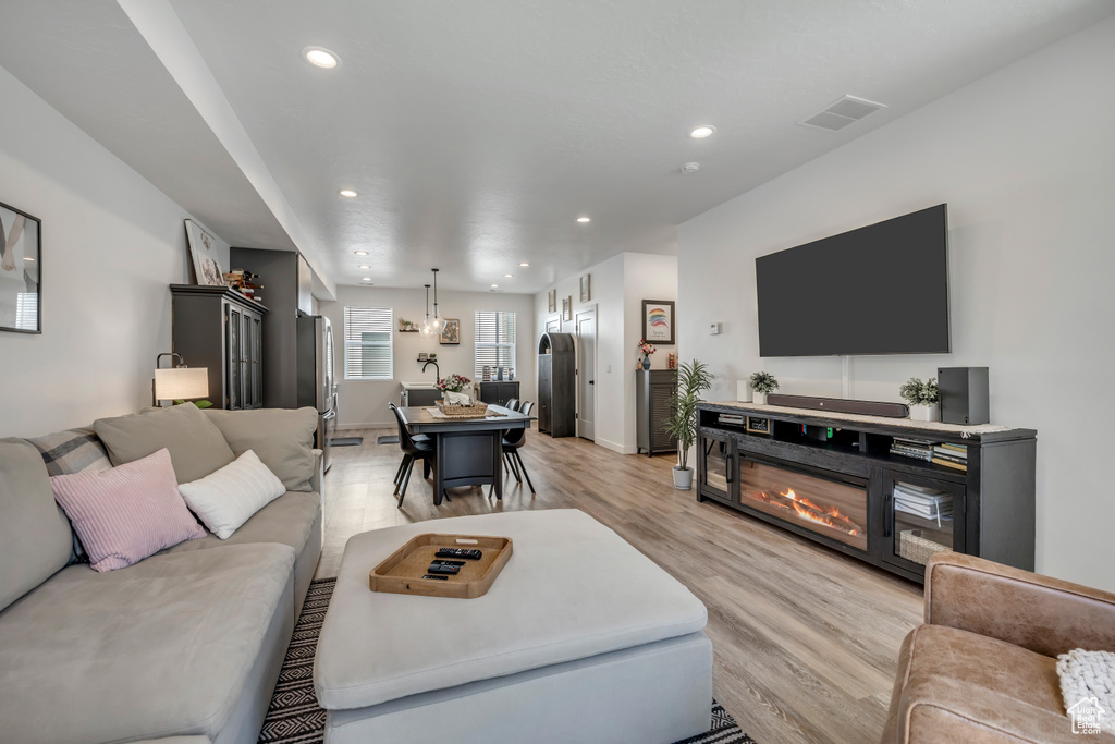 Living area featuring light wood-style flooring, recessed lighting, and a glass covered fireplace