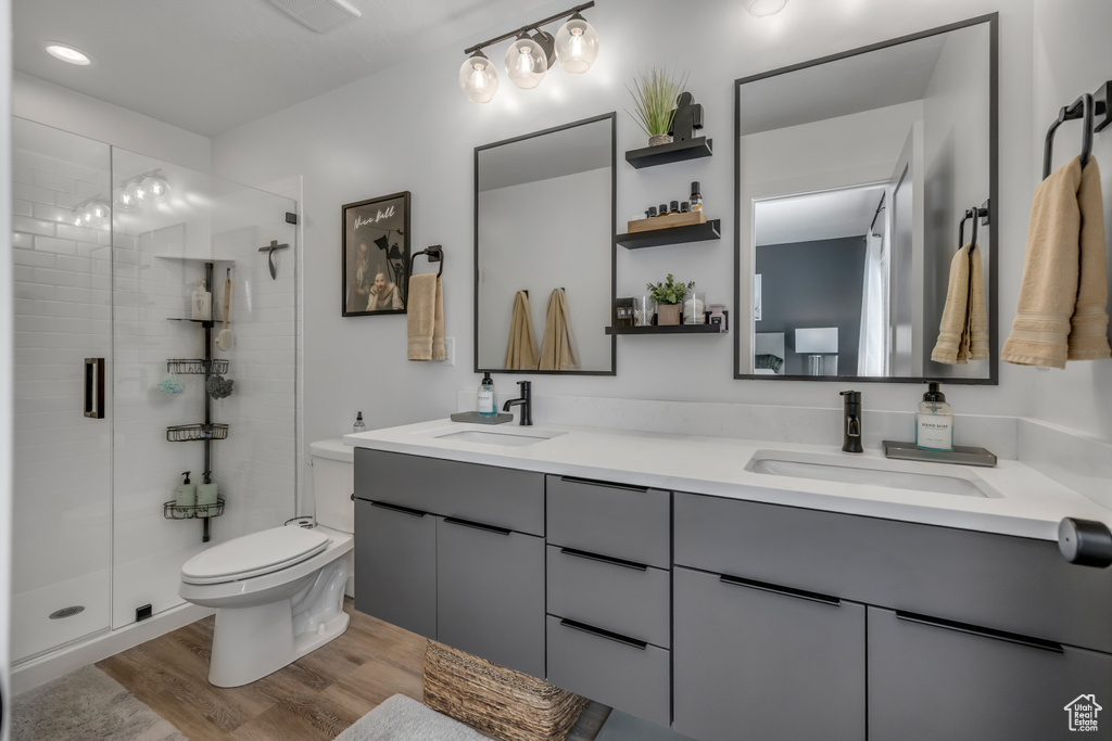 Full bath featuring double vanity, a stall shower, wood finished floors, and recessed lighting