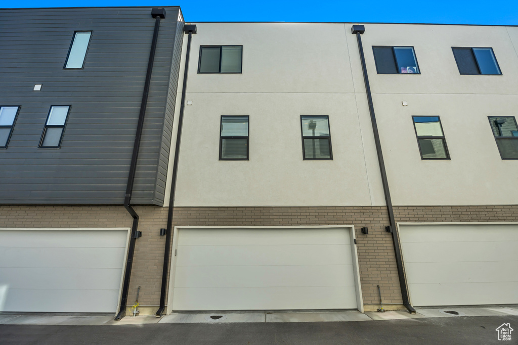 Rear view of property with an attached garage and brick siding