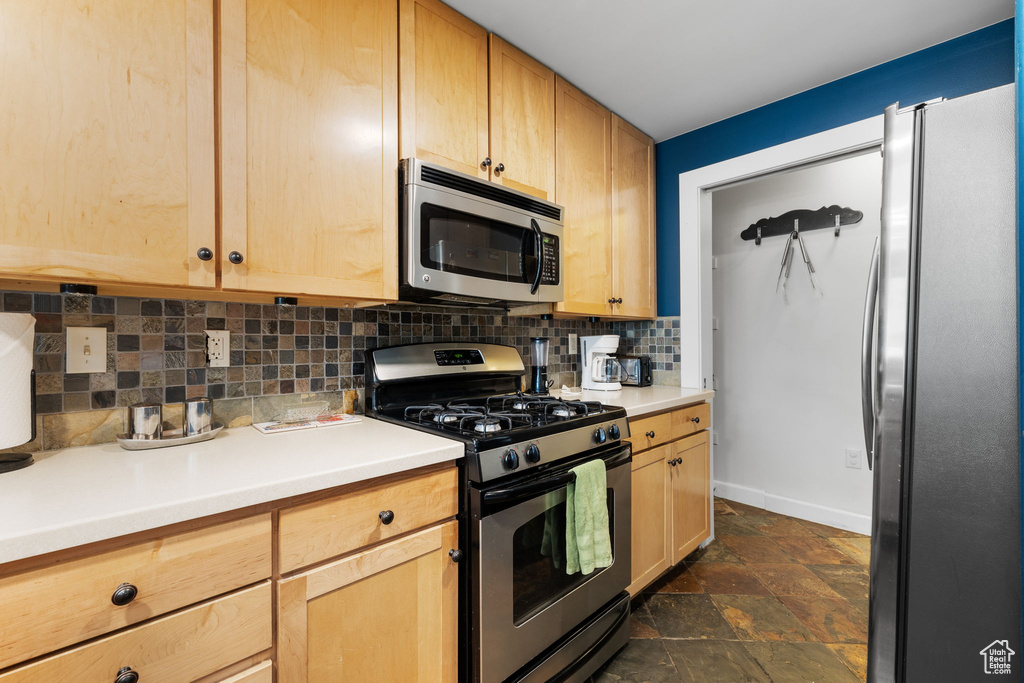 Kitchen featuring stainless steel appliances, light brown cabinets, and tasteful backsplash
