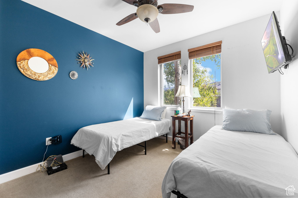 Carpeted bedroom with a ceiling fan and baseboards