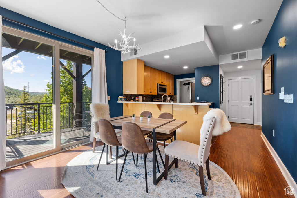Dining space featuring wood finished floors, a chandelier, baseboards, and recessed lighting