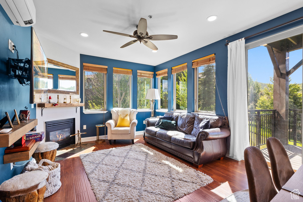 Living room featuring an AC wall unit, a fireplace with flush hearth, ceiling fan, recessed lighting, and wood finished floors