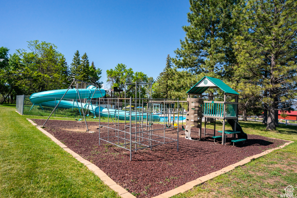 Communal playground featuring a yard and view of scattered trees