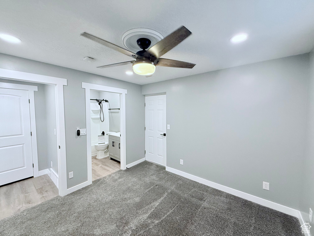 Unfurnished bedroom featuring carpet, ensuite bath, a ceiling fan, and wood finished floors