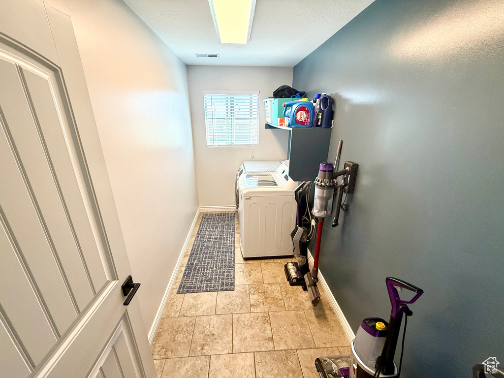 Laundry area with independent washer and dryer and light stone finish flooring