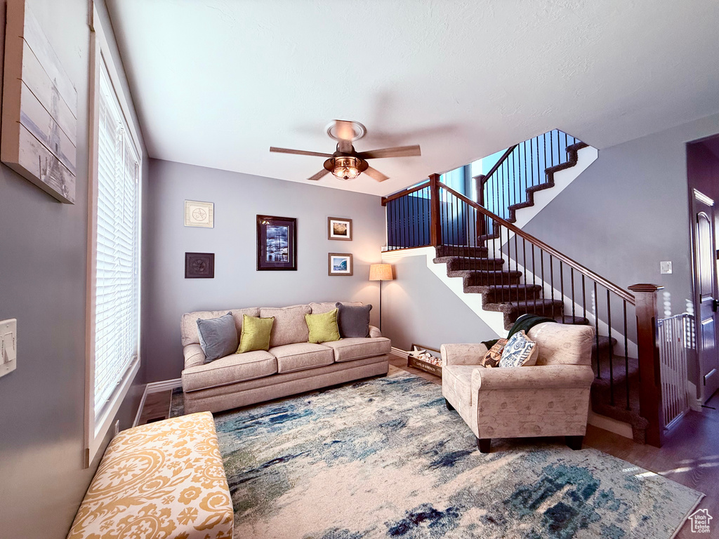Living area with stairs, wood finished floors, and a ceiling fan