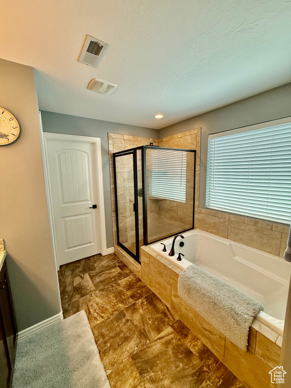 Bathroom with a garden tub, a stall shower, vanity, and a textured ceiling