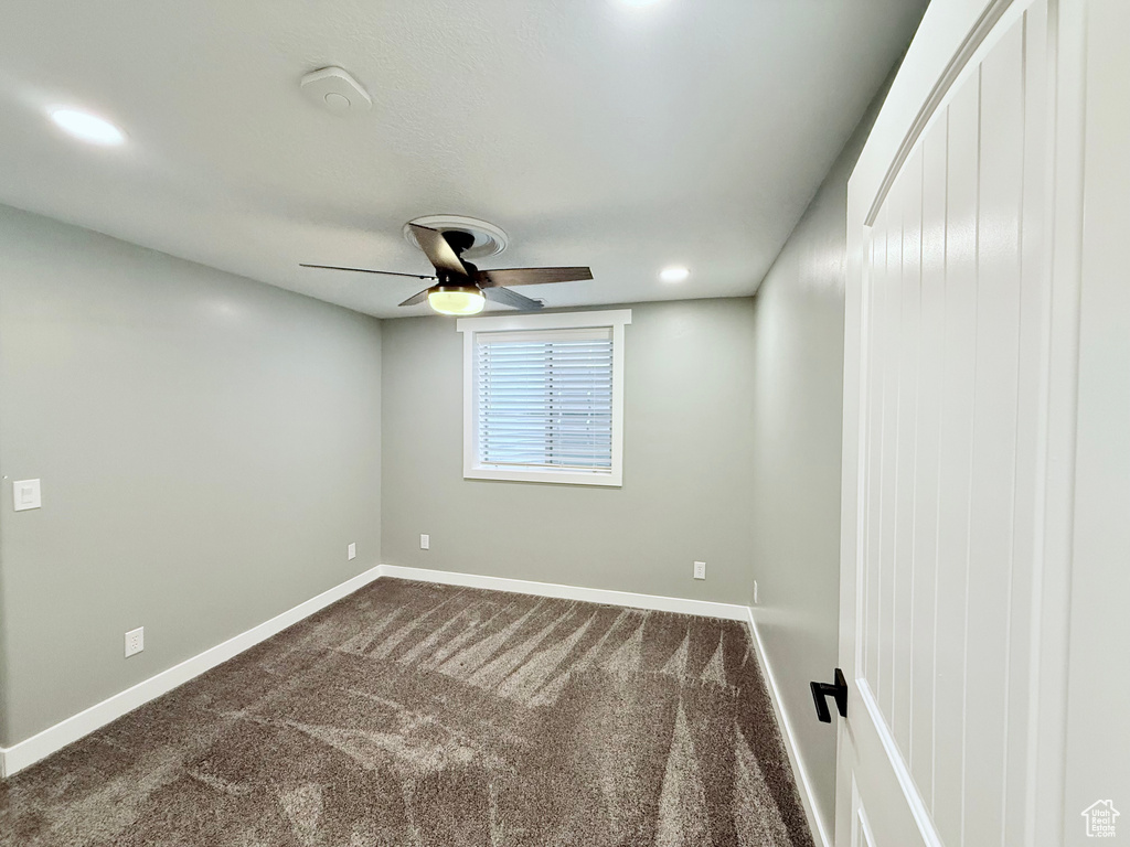 Spare room featuring ceiling fan and dark carpet
