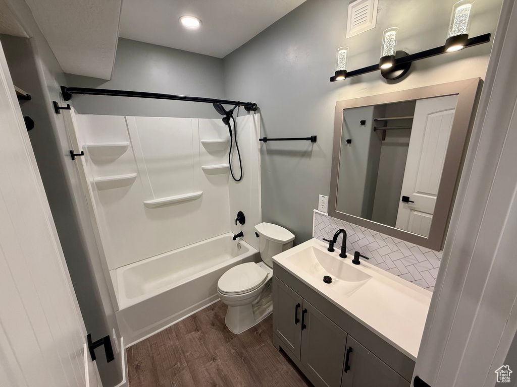 Full bath with wood finished floors, tasteful backsplash, vanity, and shower / washtub combination