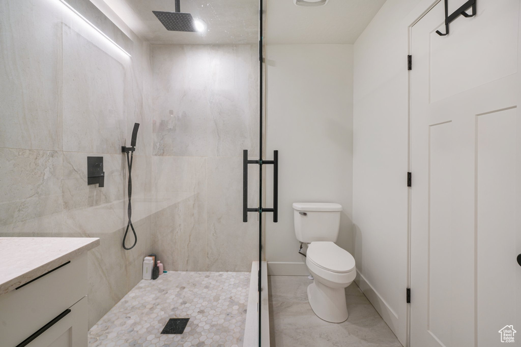 Bathroom with a marble finish shower, marble finish flooring, and vanity