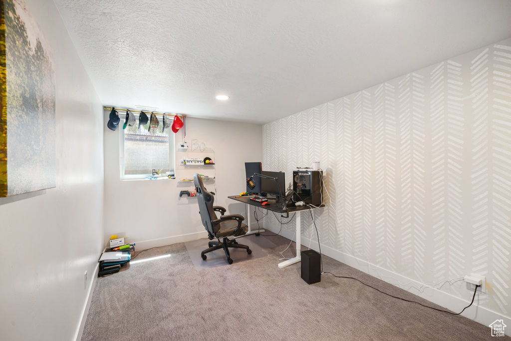 Carpeted office space with wallpapered walls and a textured ceiling