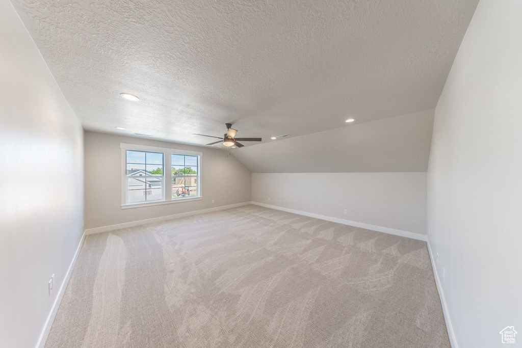 Additional living space featuring a textured ceiling, ceiling fan, light carpet, vaulted ceiling, and recessed lighting