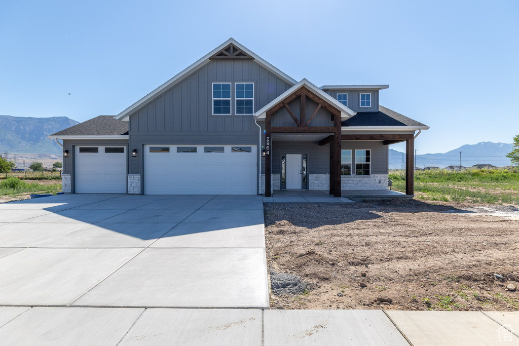 View of front facade with a mountain view, a porch, concrete driveway, a garage, and board and batten siding