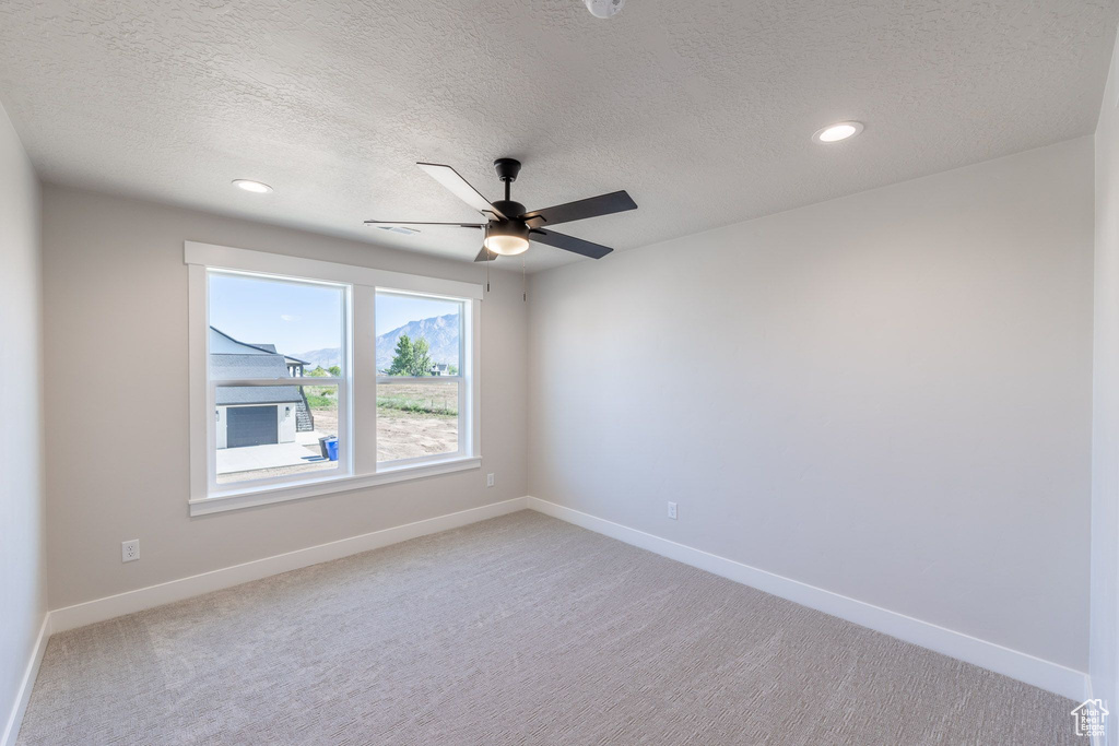 Empty room featuring light carpet, ceiling fan, a textured ceiling, and recessed lighting