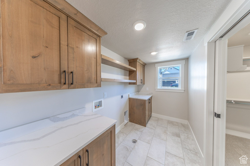 Laundry area with cabinet space, hookup for an electric dryer, hookup for a washing machine, a textured ceiling, and recessed lighting