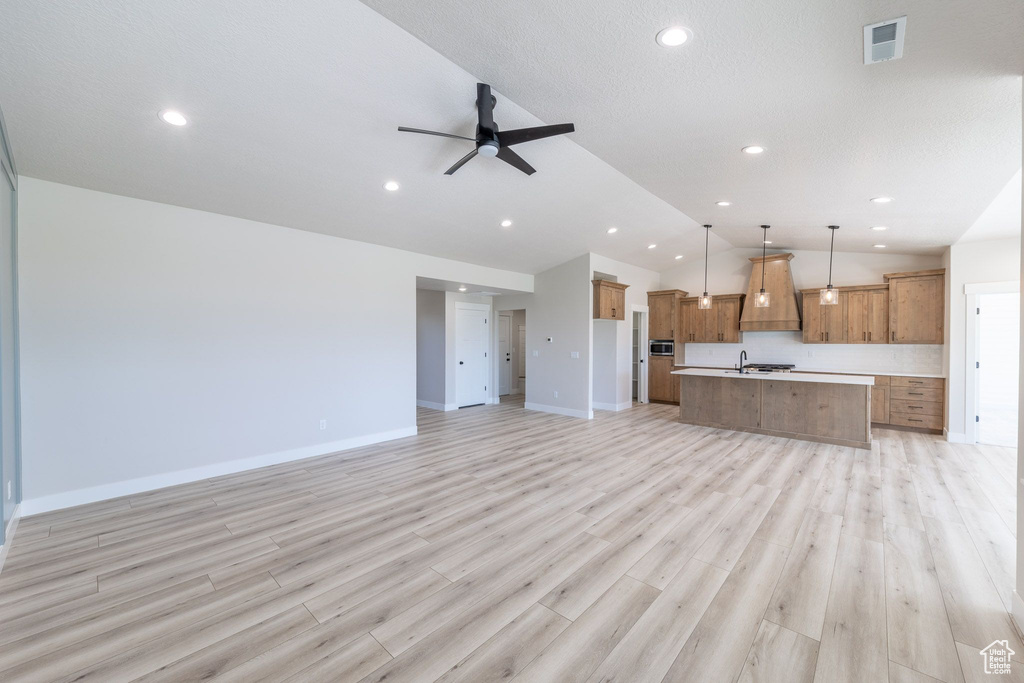 Unfurnished living room featuring a ceiling fan, recessed lighting, lofted ceiling, and light wood-style floors