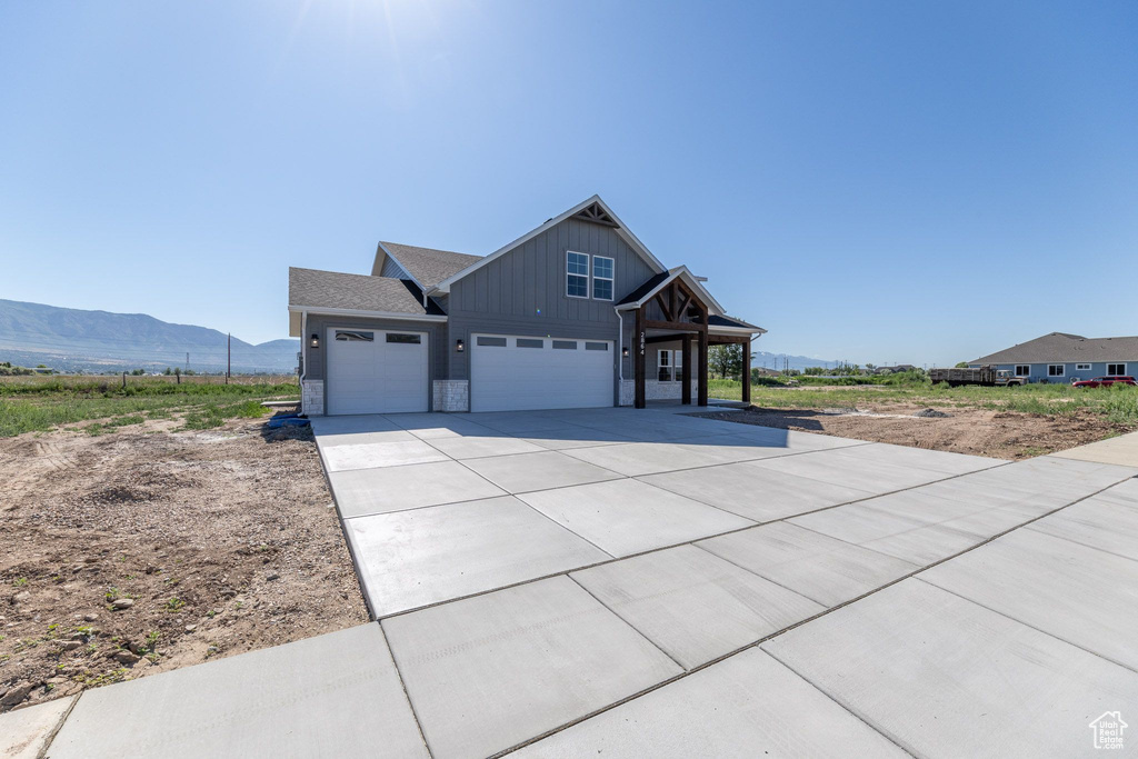 Craftsman-style house with board and batten siding, a mountain view, driveway, an attached garage, and a garage