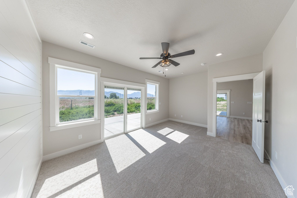 Empty room featuring light carpet, healthy amount of natural light, ceiling fan, and recessed lighting
