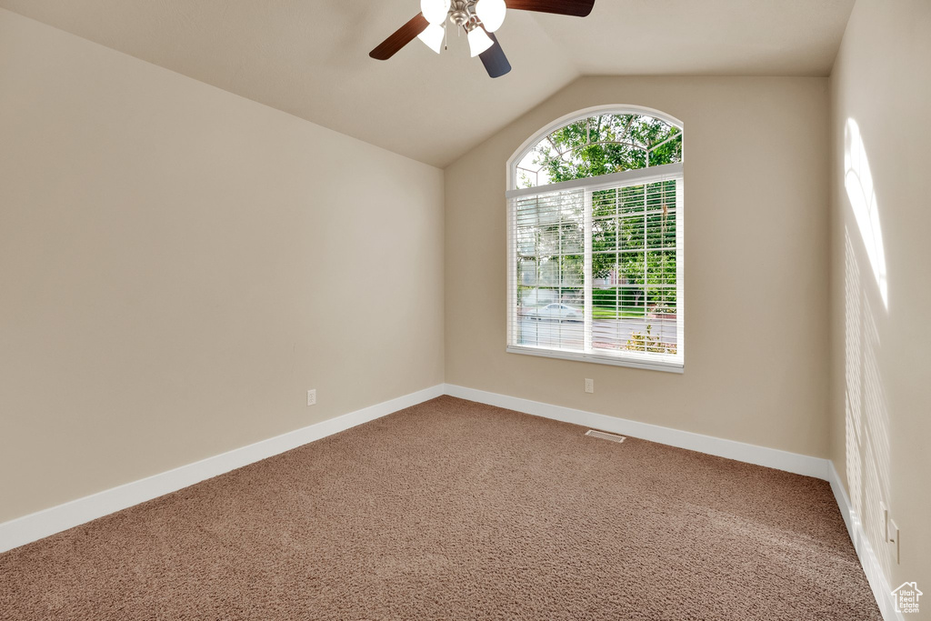 Unfurnished room with a ceiling fan, carpet floors, and lofted ceiling