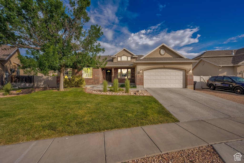 View of front of home featuring driveway, an attached garage, brick siding, and stucco siding